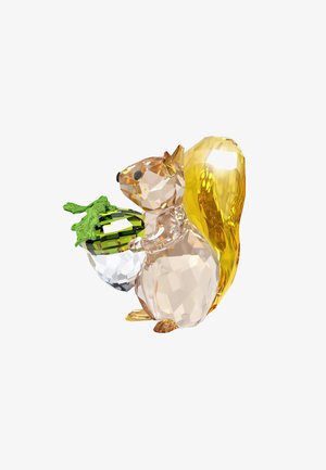 Figurka w kształcie wiewiórki z kryształu, w przezroczystych i bursztynowych odcieniach, trzymająca żołądź z zielonym akcentem, o fasetowanym designie, który ukazuje załamanie światła i szczegóły.