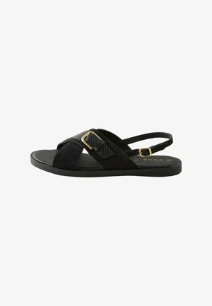 Sorte sandaler med en kombination af ruskind og tekstureret materiale, der har krydsede stropper og en guldbeslagsdetalje. Flad sål.