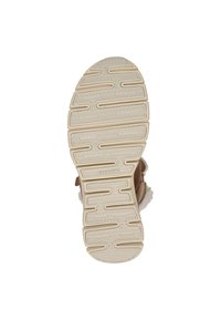 Suola della scarpa caratterizzata da un design in gomma beige testurizzato con scanalature e cerchi per una maggiore aderenza, abbinata a una parte superiore in pelliccia sintetica marrone.