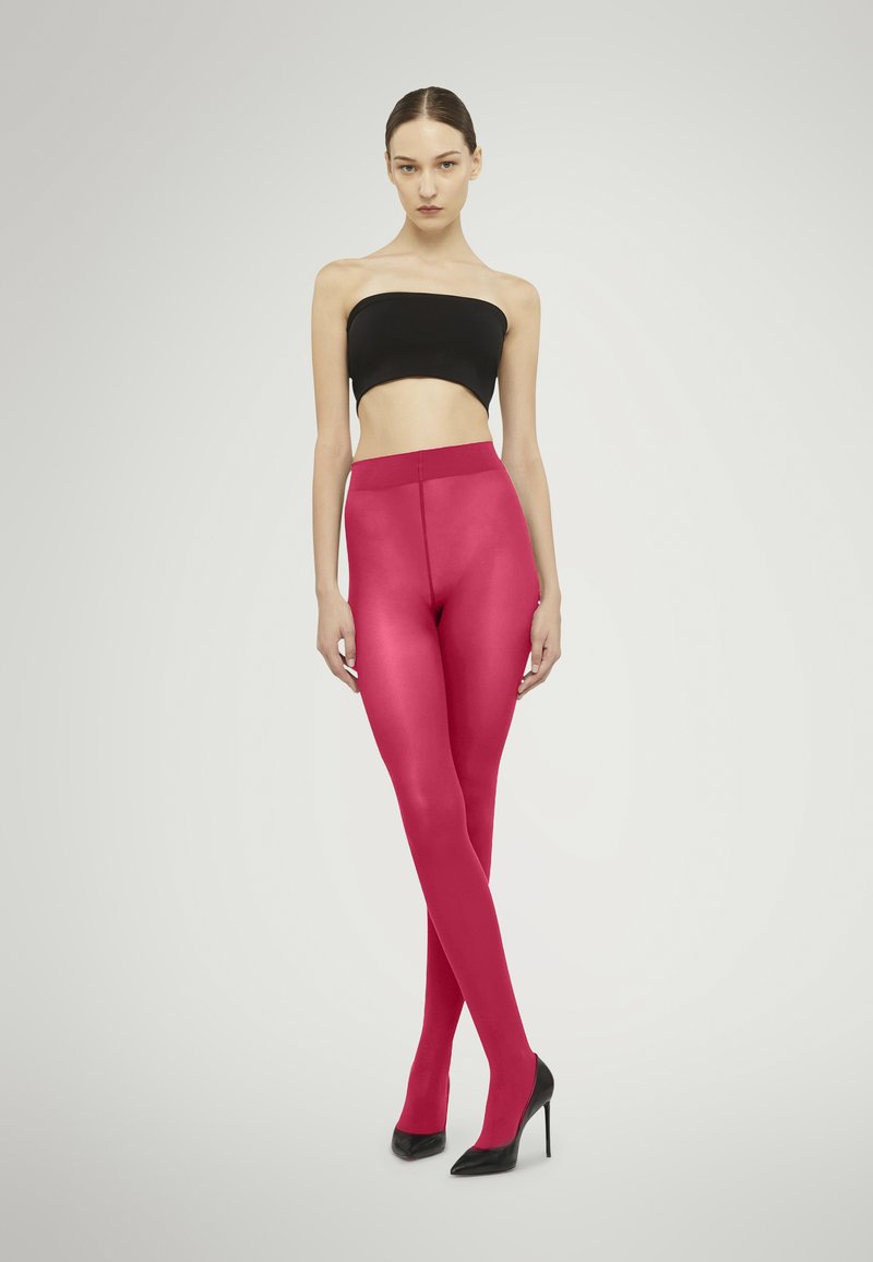I leggings fucsia presentano una finitura liscia e una vita alta, abbinati a un top bandeau nero e a scarpe nere con tacco alto.