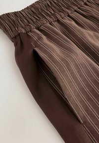 Bruine gestreepte rok met een geplooide elastische tailleband, met een soepele textuur en zijzakken, in een vloeiende stijl.