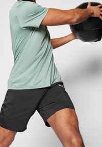 Ropa deportiva que incluye una camiseta de manga corta verde menta y pantalones cortos negros, fabricados con un tejido ligero y transpirable, con detalle de logo en los pantalones cortos.