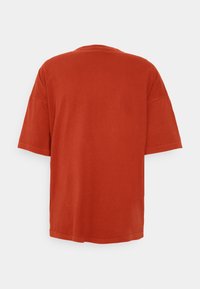 Camiseta de algodón roja de manga corta, con un corte holgado y un escote redondo. Diseño simple sin patrones ni acentos visibles.
