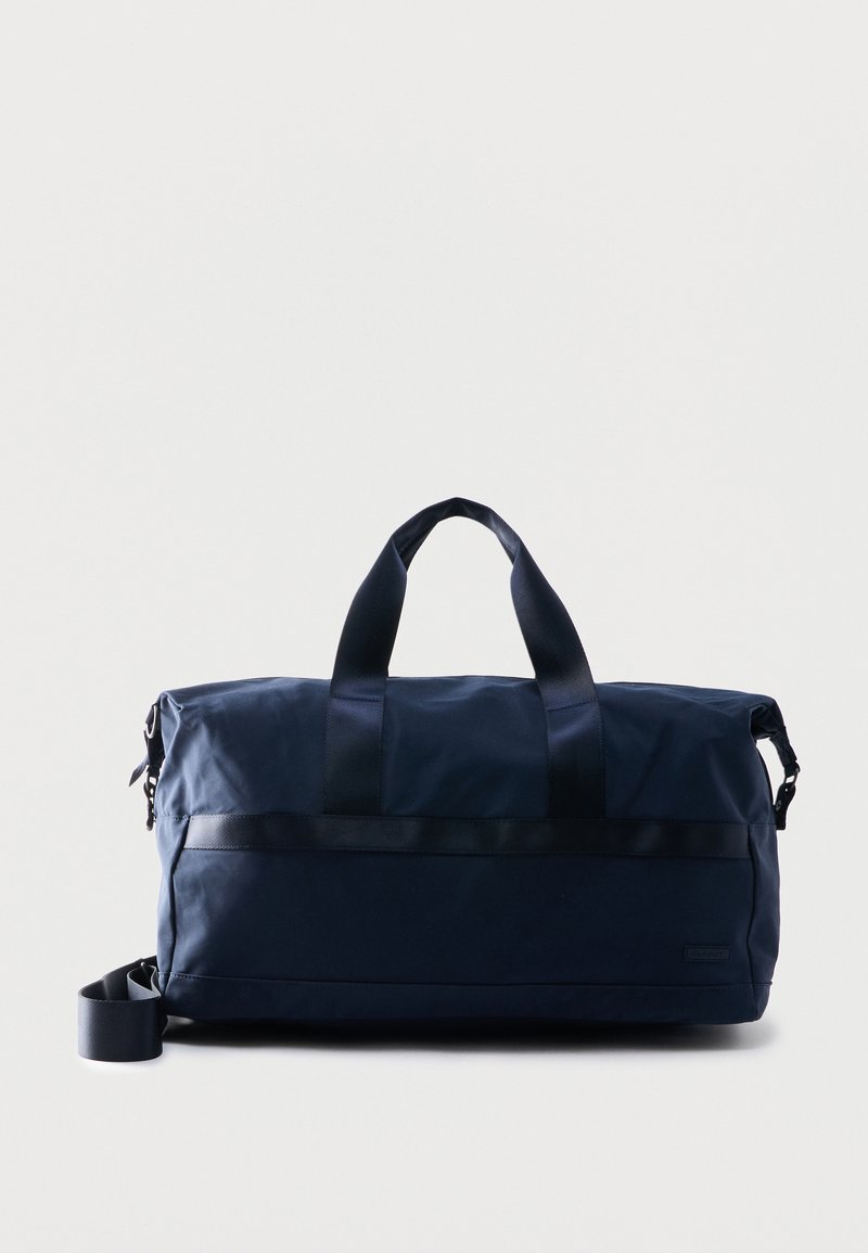 Σκούρο μπλε σακ βουαγιάζ με διπλές λαβές tote και ρυθμιζόμενο ιμάντα ώμου σε απλό ανοιχτό φόντο.