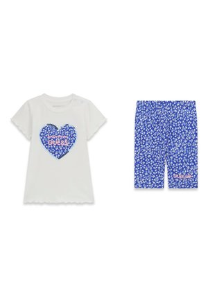 Top bianco a maniche corte con cuore floreale blu e scritta "Guess", abbinato a pantaloncini blu floreali fino al ginocchio con piccoli fiori bianchi.