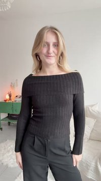 Musta ribattava neule ponnistusolkapäillä, pitkät hihat ja tiukka siluetti, yhdistettynä mustiin korkeavyötäröisiin housuihin. Teksturoitu kangas.