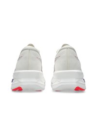 Baskets blanches avec un dessus en tissu texturé, présentant un design coloré sur le talon, avec des accents rouges et violets contrastants sur la semelle.