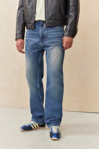 Dark leather jacket, light t-shirt, blue denim jeans with a faded finish, and blue sneakers with cream stripes and laces. Casual outfit.