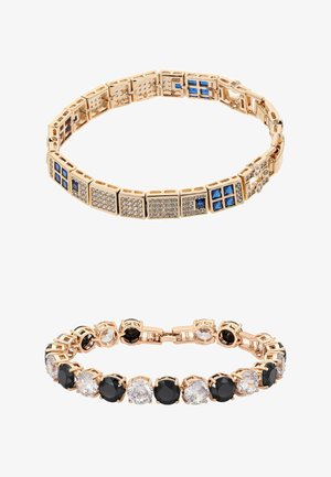 Dwie złote bransoletki: jedna z niebieskimi kwadratowymi i przezroczystymi okrągłymi kamieniami w połączonych kwadratach, druga z naprzemiennie dużymi czarnymi i przezroczystymi okrągłymi kamieniami.