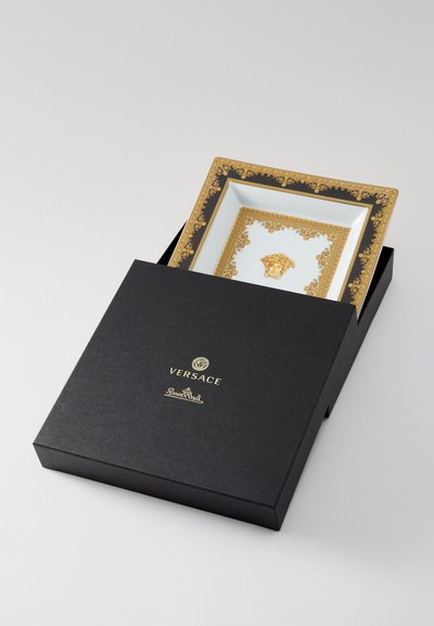 Versace dekoratīvā šķīve ar zelta un melnu dizainu, centrālā logotipa un greznu apmali, prezentēta melnā kastītē.