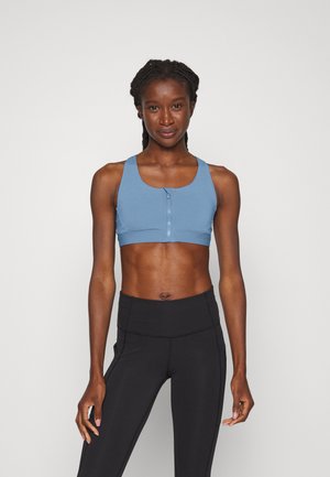 Top cropped atlético azul com fecho à frente, alças largas e um design ajustado, combinado com leggings pretas de cintura alta.