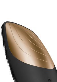 Brosse à cheveux noire et dorée avec un design incurvé ; présente une surface dorée nervurée et de douces brins noirs sur le bord.
