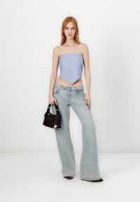 Top bez ramínek s modro-bílými pruhy a špičatým lemem, kombinovaný se světle modrými rozšířenými džínami a malou černou kabelkou.