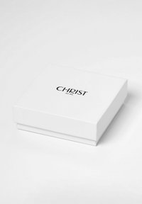 Witte vierkante doos met het woord "CHRIST" en "seit 1863" in het zwart gecentreerd afgedrukt op het deksel, geplaatst op een witte ondergrond.