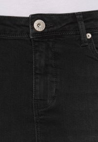 Schwarze Jeans aus Denim mit einer glatten Textur, einem silbernen Knopf am Bund und einem klassischen Fünf-Taschen-Design.