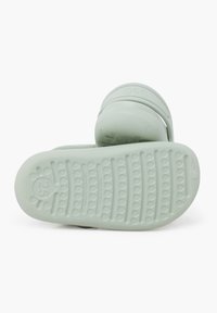 Mintgrøn gummiklæd med en tekstureret sål, der har et logo på stropen og rund form. Egnet til afslappet brug. Størrelsen er markeret som 25.