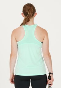 Mintgrön träningslinne med racerback-design, tillverkat av lätt och slätt material och med en smal passform.