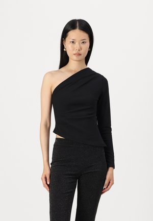 Top nero a spalla sola in un materiale elasticizzato, caratterizzato da una vestibilità aderente e un design asimmetrico. Abbinato a pantaloni neri scintillanti.