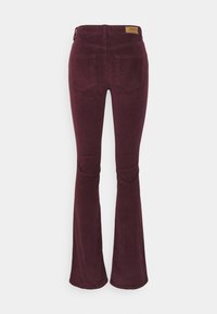 Burgundy corduroy flared pants with a textured surface, featuring two back pockets and a tan brand label at the waist.