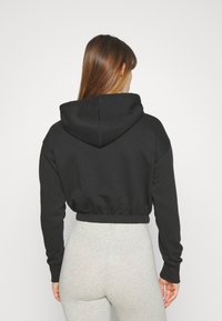 Felpa nera tagliata con cappuccio regolabile, orlo e polsini a costine. Tessuto morbido, vestibilità comoda e design minimalista.