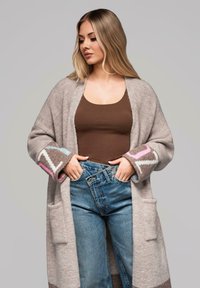 Cardigan lavorato a maglia oversize grigio chiaro con maniche decorate da motivi in marrone, rosa e blu, dotato di tasche frontali e vestibilità comoda.