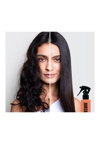 Immagine divisa che mostra una donna con capelli ricci a sinistra e capelli lisci a destra. Un flacone spray con un'etichetta arancione si trova in basso a destra.