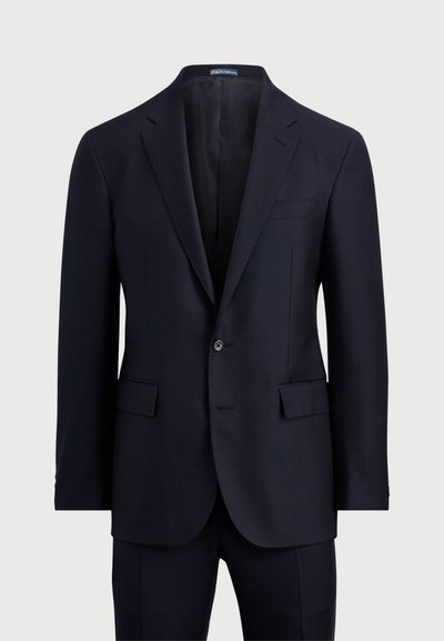 Jūras zila uzvalka žakete ar griezumu atlokiem, vienu pogu, divām priekšējām kabatām un gludu tekstūru. Pielāgota piegriezuma ar smalkiem šuvumiem.