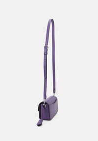 Fialová kožená crossbody taška s tenkým nastavitelným popruhem, obdélníkovým tvarem, hladkou texturou a malou visačkou připevněnou k zipu.