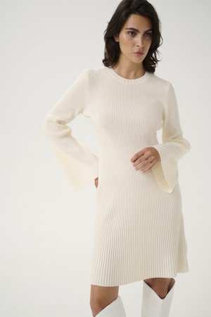 Rochie din tricotare ribbed, de culoare crem deschis, cu maneci lungi tip clopot si decolteu rotund, avand o linie de tiv evazata pentru un fit confortabil.