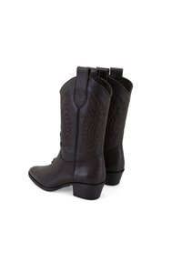 Bottes de cowboy en cuir marron avec des coutures détaillées, une tige de hauteur moyenne et des brides de tirage. Talon bloc et finition texturée sur le matériau.