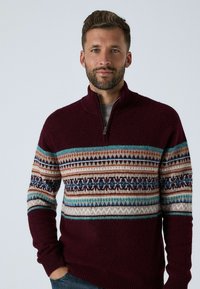 Bordeaux gekleurde gebreide trui met een halve rits, voorzien van verschillende geometrische ontwerpen in beige, blauw en bruin, en ribgebreide manchetten en zoom.