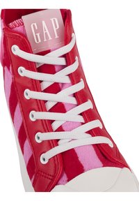 Baskets à carreaux rouges et roses avec lacets blancs, semelle blanche et logo GAP sur la languette.