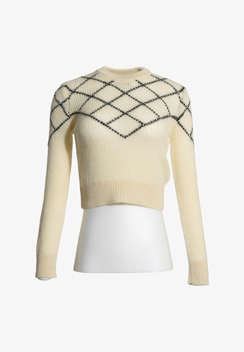 Pull en maille crème à manches longues avec motif losange noir sur la poitrine et les épaules sur un torse de mannequin blanc.