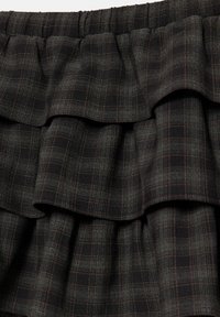 Tissu à carreaux noirs et gris foncé avec un design superposé froncé et une ceinture élastique.