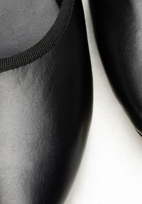 Schwarze Lederflats mit glatter Textur, abgerundetem Zehenbereich und elastischem Besatz am Öffnungsrand für Komfort und Passform.
