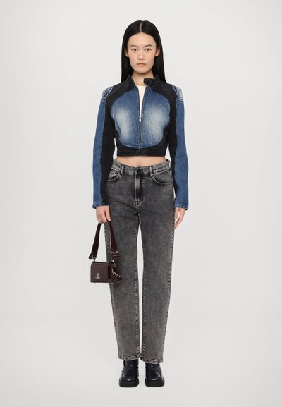 Cropped denim jacket featuring light and dark blue sections, zip closure, and high collar, paired with gray straight-leg jeans and a small burgundy bag.