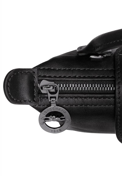 Black leather handbag featuring textured surface, a silver zipper with a charm, and stitched detailing along the edges.
