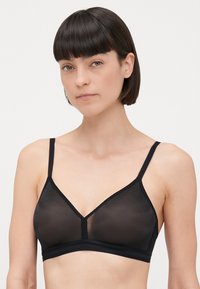 Mustmust mustraga, mis on valmistatud õhukesest kangast, kolmnurksete tassidega, reguleeritavad rihmad ja õrn pitsikand sümmeetriliselt servade ja vöö kohta.