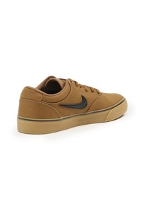 Brown canvas sneaker with a low-top design, black swoosh logo, rounded toe, and rubber outsole. Features textured fabric and flat laces.