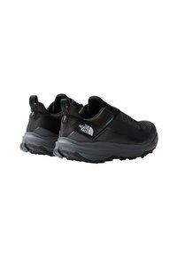 Scarpe da trekking nere con tomaia testurizzata, tacco rinforzato e suola robusta in gomma grigia. Presentano un dettaglio logo di lato e linguette di trazione.
