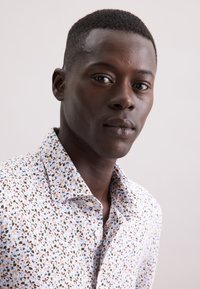 Bloemmotief, button-up shirt in lichte kleuren met groene, bruine en blauwe accenten. Katoenen stof, met een spreidkraag en een ontspannen pasvorm.