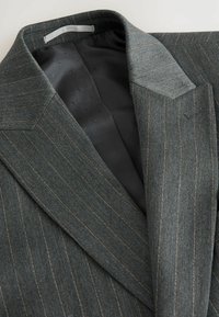 Grau gestreifter Blazer mit scharfen Revers. Verfügt über ein glattes schwarzes Futter. Vertikale Streifen stehen im Kontrast zu dem strukturierten Stoff. Taillierte Passform.