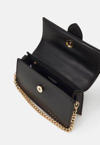 Svart läderkuvert med guldmagnetknäppning och guldkedjeaxelrem, öppnas för att visa inre blixtlåsfack och slät innervägg.