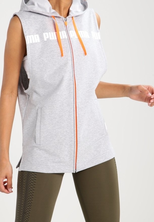 Šedá sleeveless mikina s kapucí s oranžovým zipem a stahovacími šňůrkami. Má logo na hrudi, boční kapsy a měkký, texturovaný materiál.
