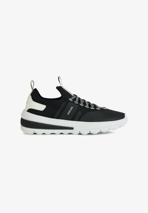 Zapatilla negra con parte superior de malla, acentos blancos y suela texturizada. Presenta un diseño de cordones y una lengüeta para ponerlas con facilidad. Logo de la marca visible.