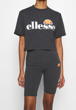 Grijs cropped t-shirt met wit "ellesse" logo, gecombineerd met grijze fietsbroekjes met een klein oranje en geel logo op het been. Gemaakt van katoen.