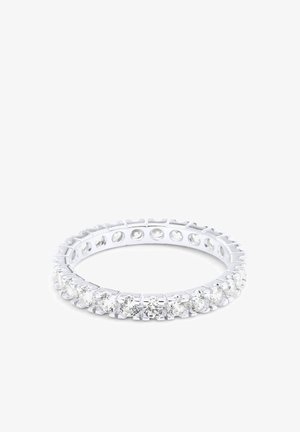 Bague anneau éternité en argent sertie de pierres précieuses rondes transparentes tout autour de l'anneau sur fond blanc.