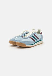 Heledad sneakers heledab sinises, tumehallid ja burgundia triibud, valged paelad ja kummist põhi. Ümar varvas ja vintage disaini detailid.