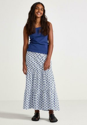 Top a canotta blu navy abbinata a una gonna bianca a balze con un motivo a diamante blu, completata da sandali neri con cinturini.