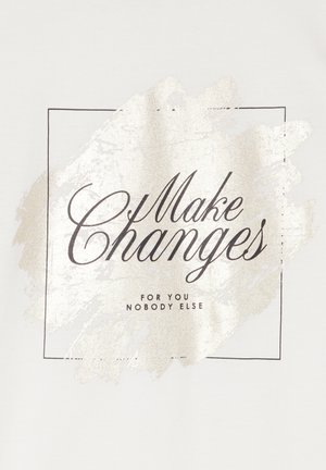 Tessuto di cotone bianco con una stampa metallica oro raffigurante il testo "Make Changes" all'interno di un contorno quadrato, con testo aggiuntivo sottostante.